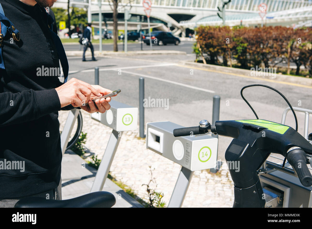 A male tourist hires a bicycle or an alternative environmental mode of transport using a mobile application on his phone. Or he simply dials a number and calls or uses the Internet on the street. Stock Photo