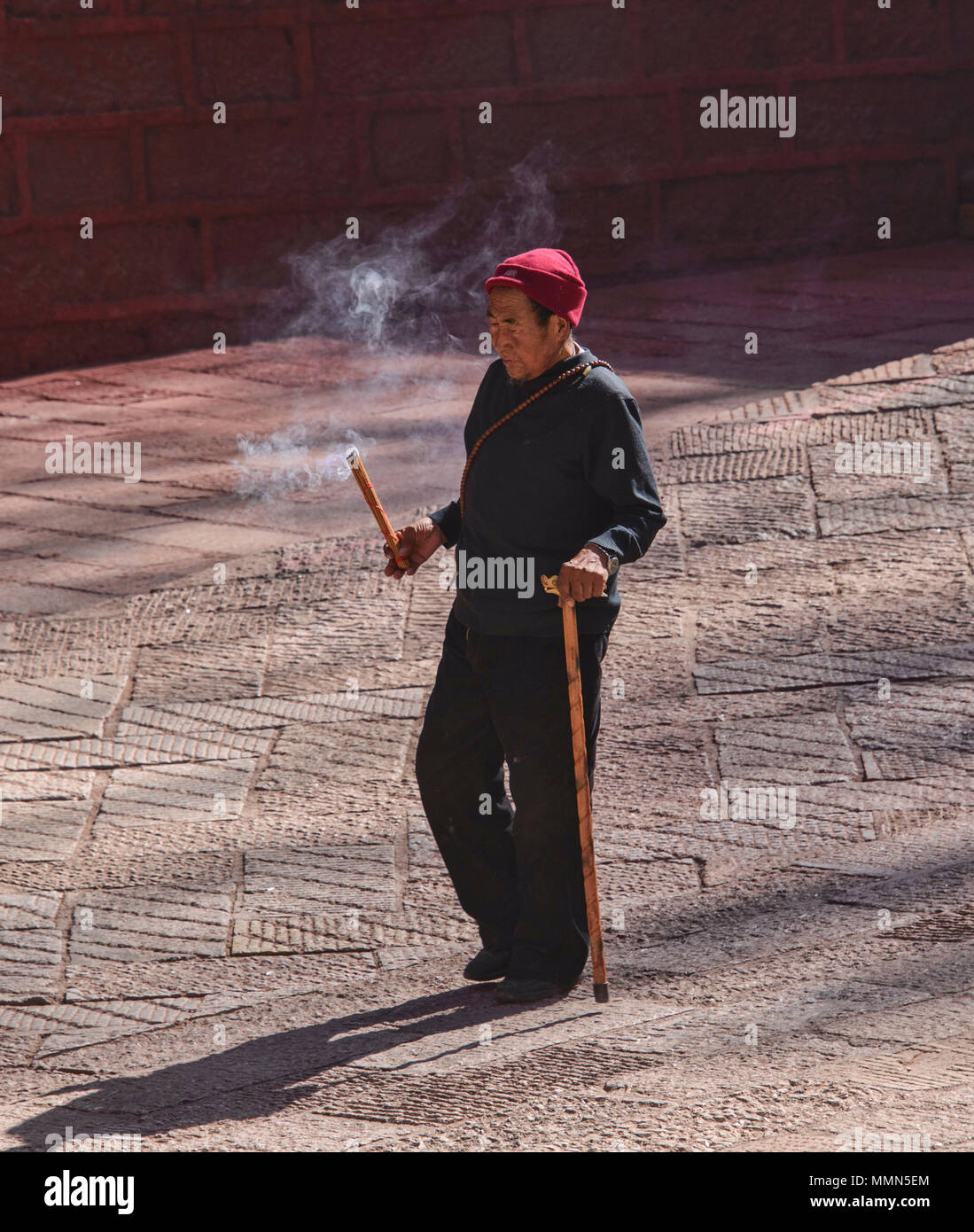 Tibetan pilgrim walks kora circles around the holy Bakong Scripture Printing Press Monastery in Dege, Sichuan, China Stock Photo