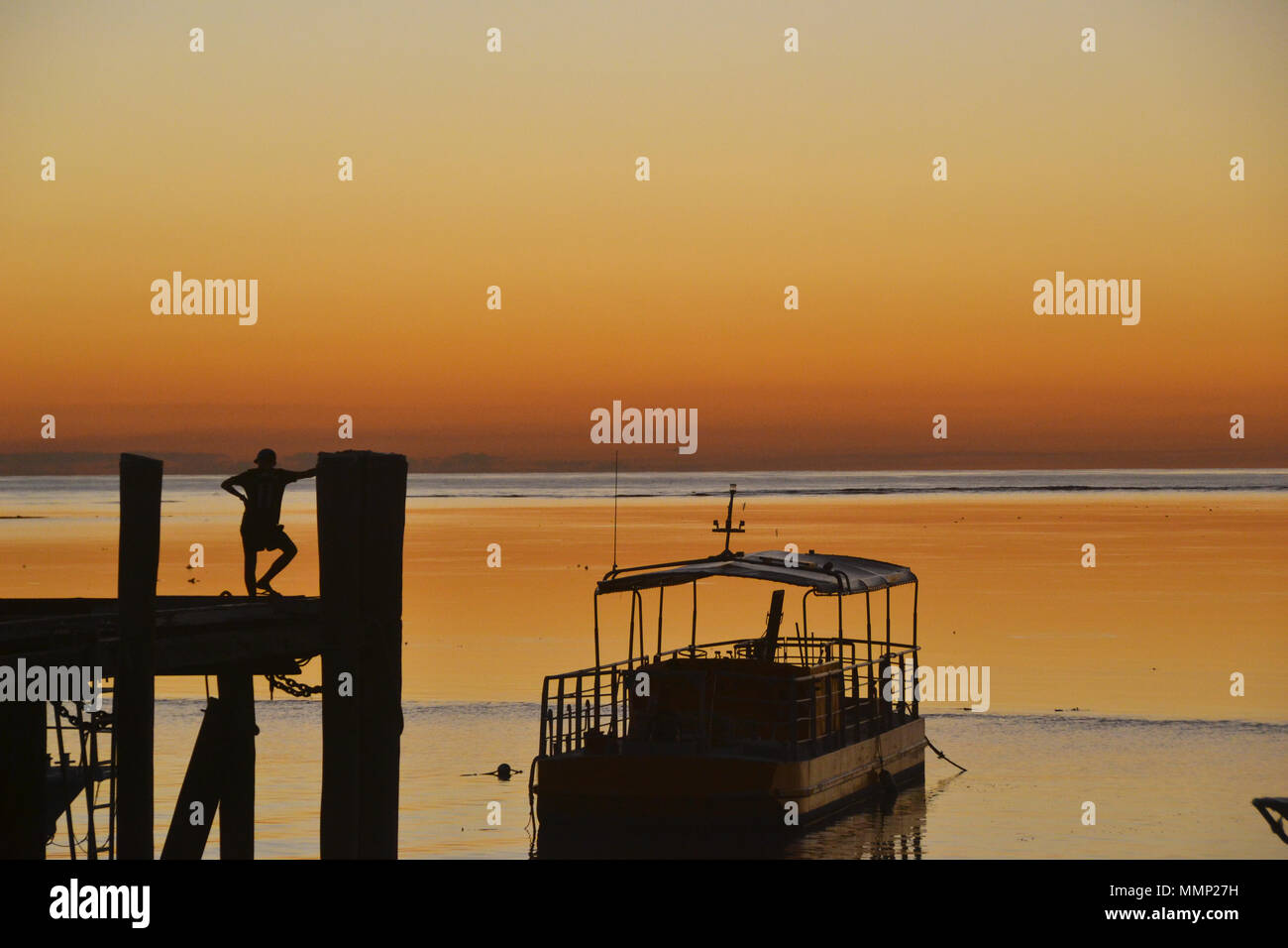 A person enjoys the golden colors of the sunset from the jetty at Heron Island, Great Barrier Reef, Queensland, Australia Stock Photo