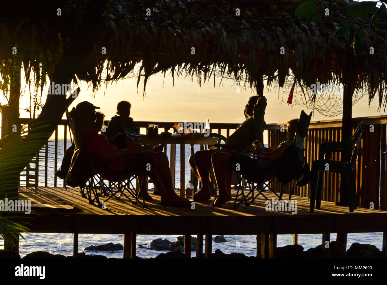 People enjoying the sunset from a bungalow by the beach, Black Coral Island, Pohnpei, Federated States of Micronesia Stock Photo