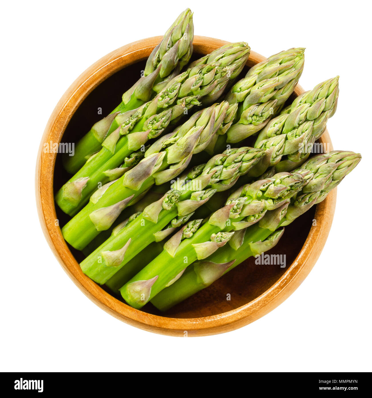 Fresh green asparagus tips in wooden bowl. Sparrow grass shoots. Cultivated Asparagus officinalis. Vegetable with thick stems and closed buds. Stock Photo