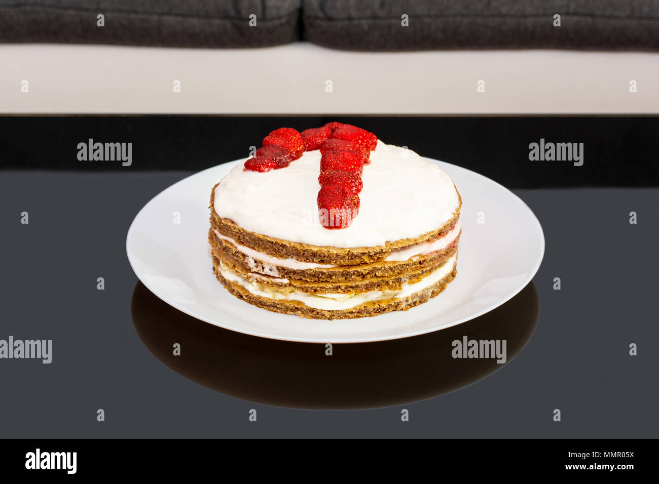 Sweet birthday cake with strawberries and number one on a white plate. Cake as a gift to your first birthday. Stock Photo