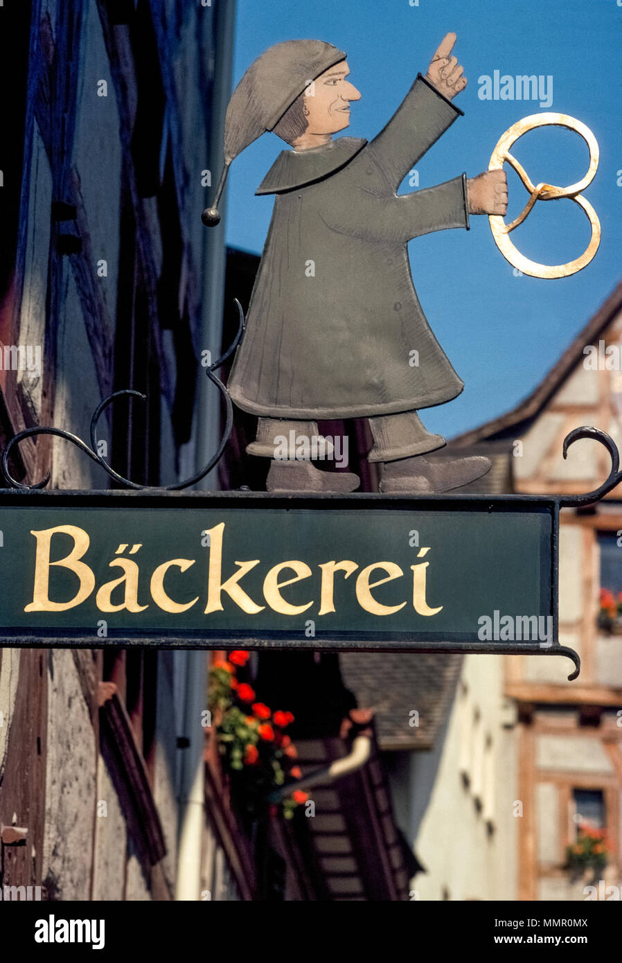 An old-fashioned outdoor guild sign that juts from a storefront depicts a baker holding a pretzel that advertises a bakery (backerei) in Stein am Rhein, Canton of Schaffhausen, Switzerland. The pretzel has been a traditional symbol for bakeries since medieval times and is thought to represent arms crossed in prayer. Stock Photo
