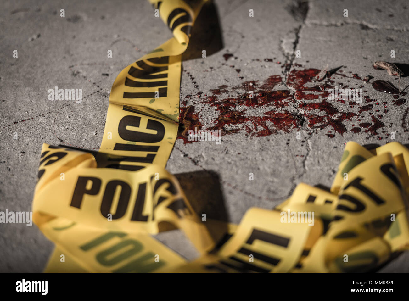 Police cordon tape lies on the ground in a small amount of blood. Stock Photo