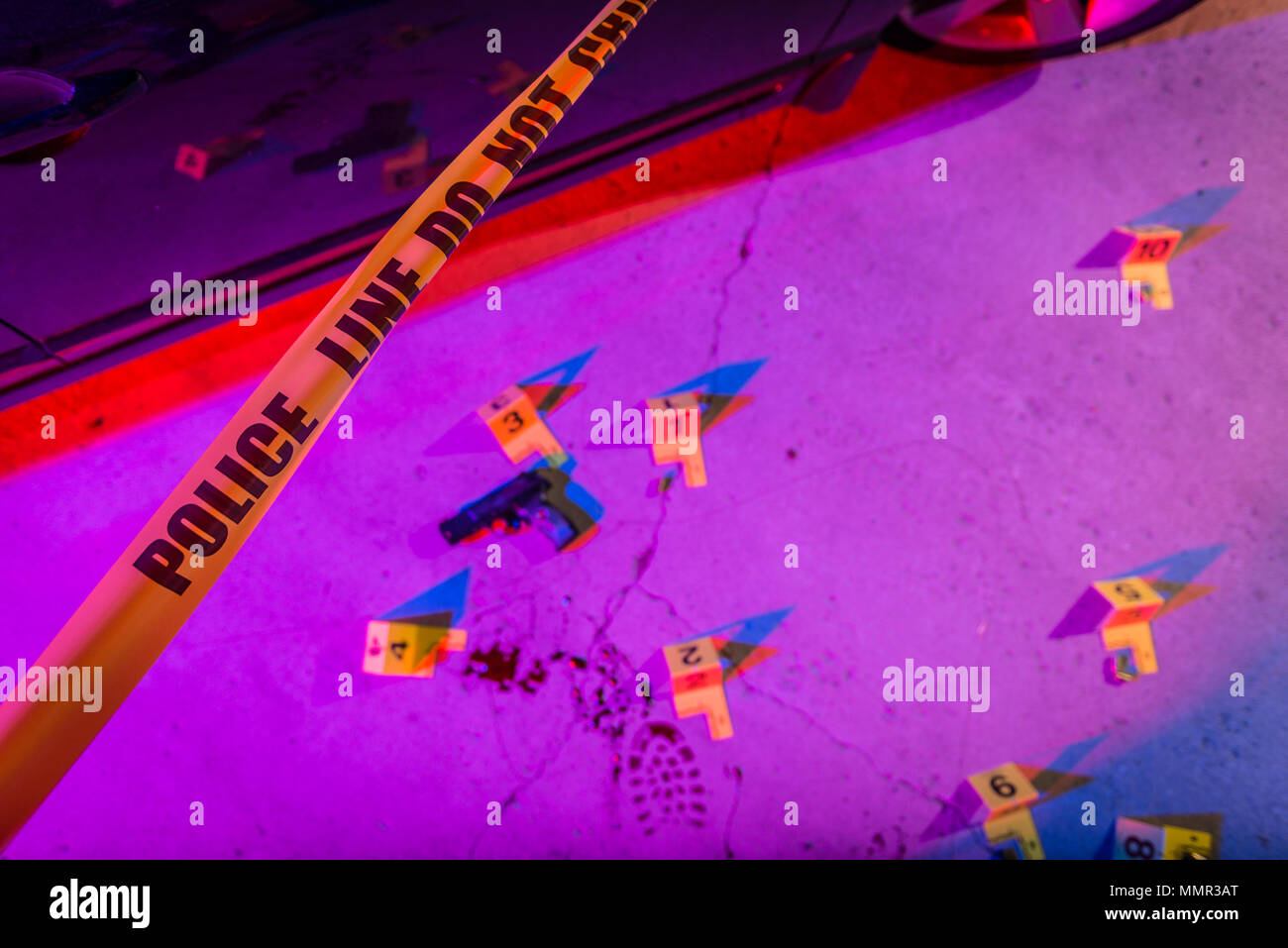 A black handgun lays on the pavement in a crime scene, marked with an evidence marker. Stock Photo