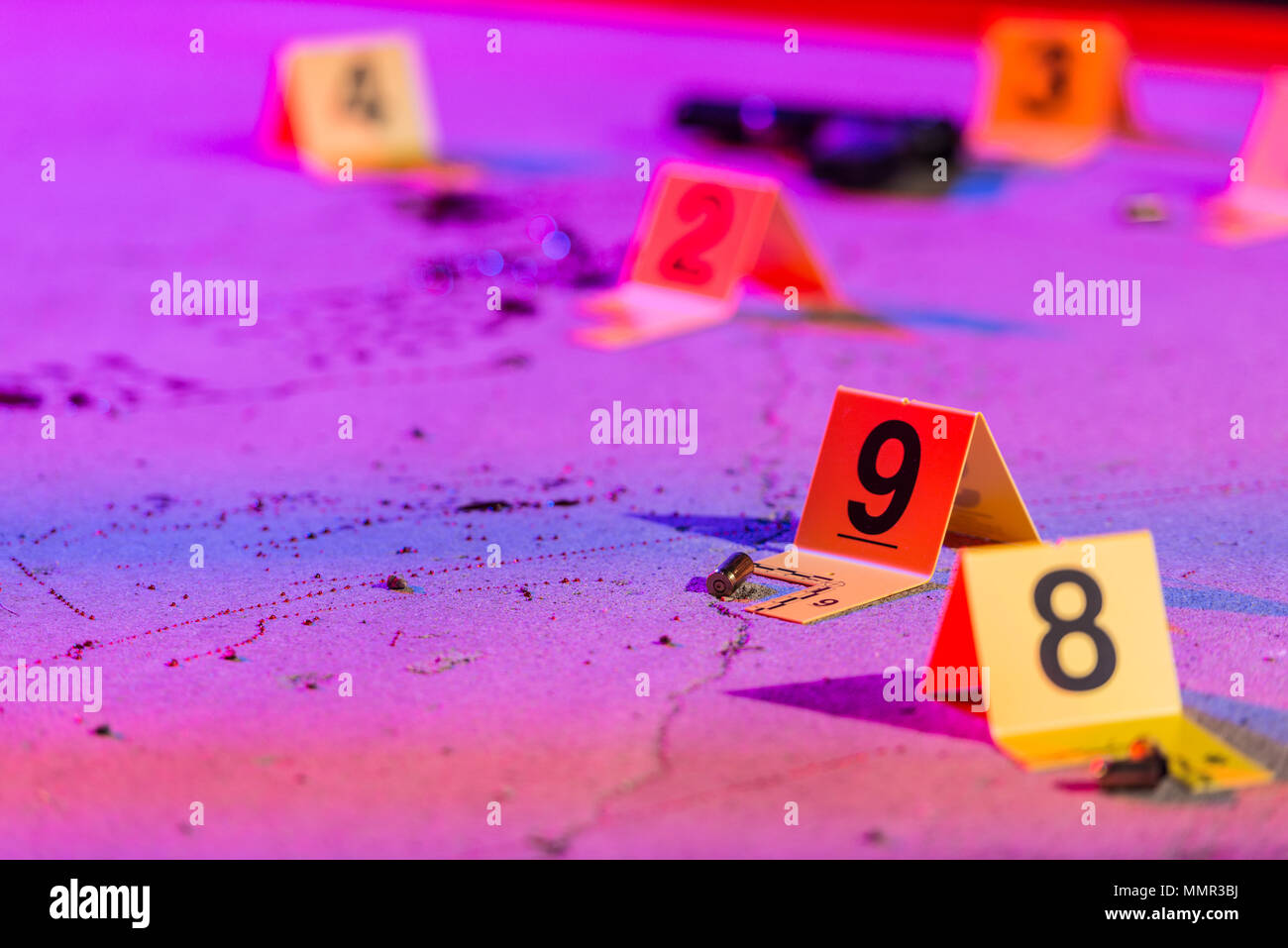 A shell casing is marked with an evidence marker within a crime scene. Stock Photo