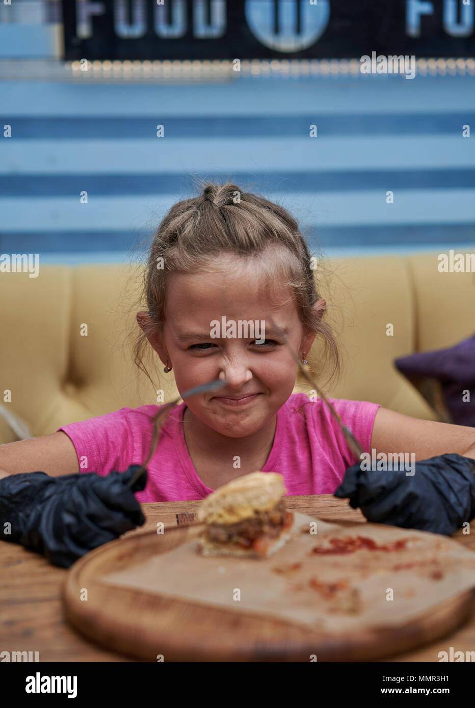 little girl eating hamburger in cafe Stock Photo