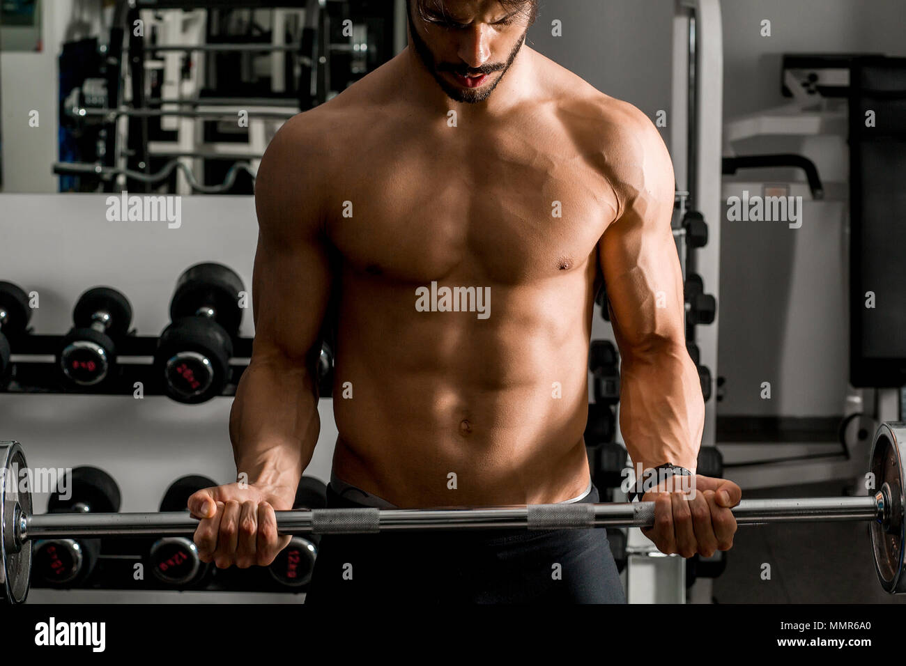 Portrait of strong and handsome young man doing exercise with dumbbells ...