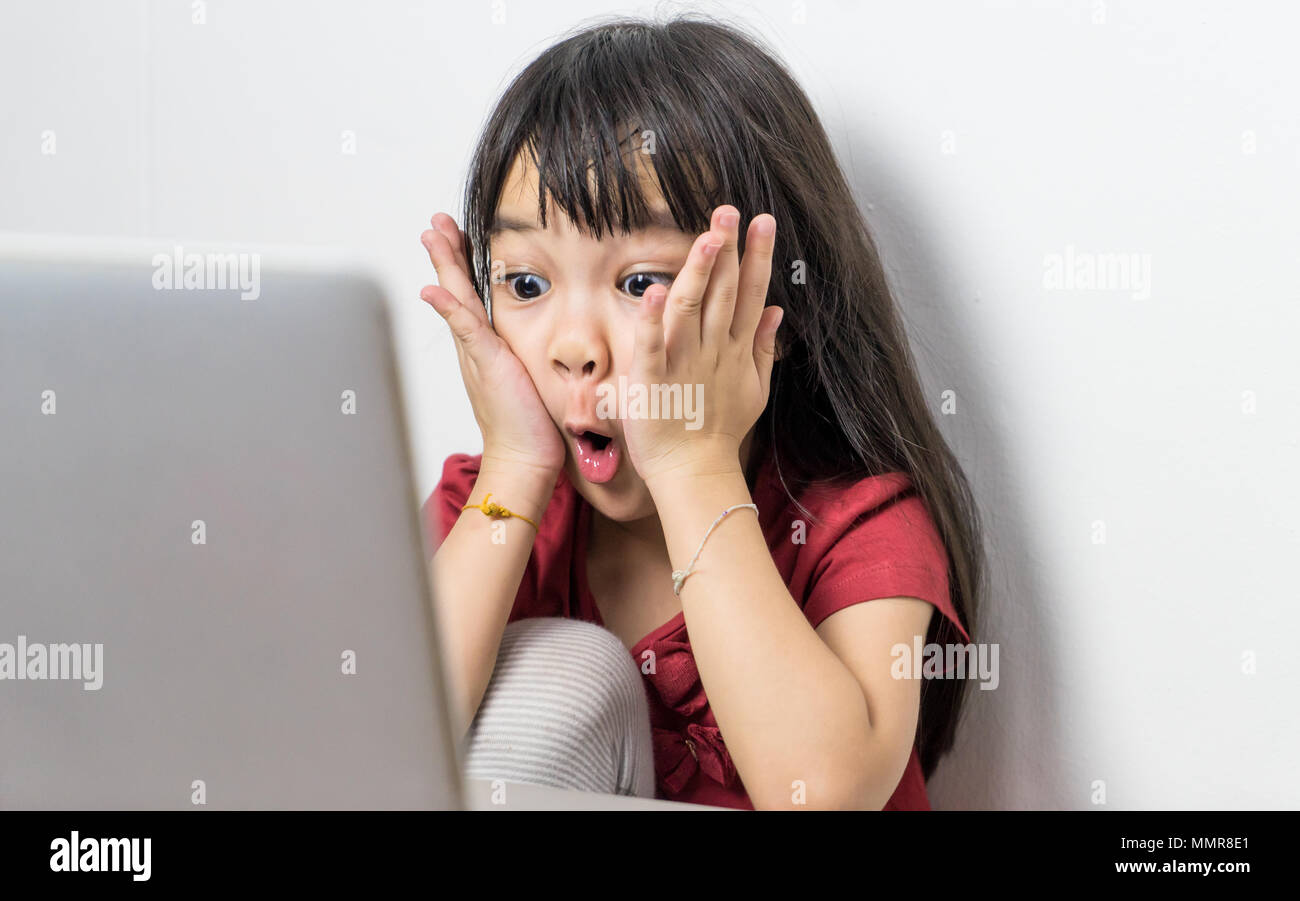 Asian kid is super surprise on something on the computer. Stock Photo