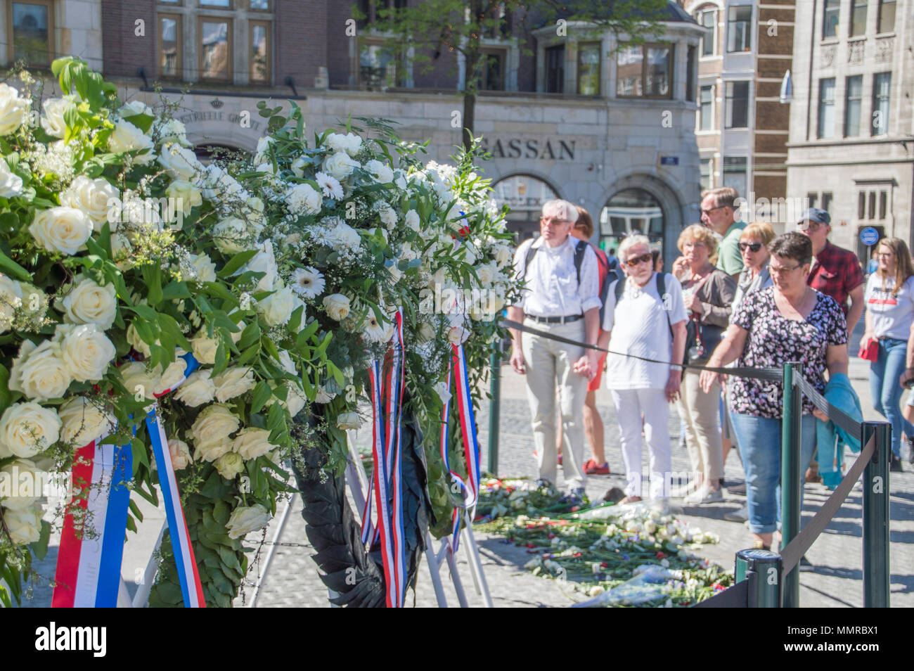 Crowd Looking At The Flowers At The Remembrance Of The Dead Statue At Amsterdam The Netherlands Stock Photo