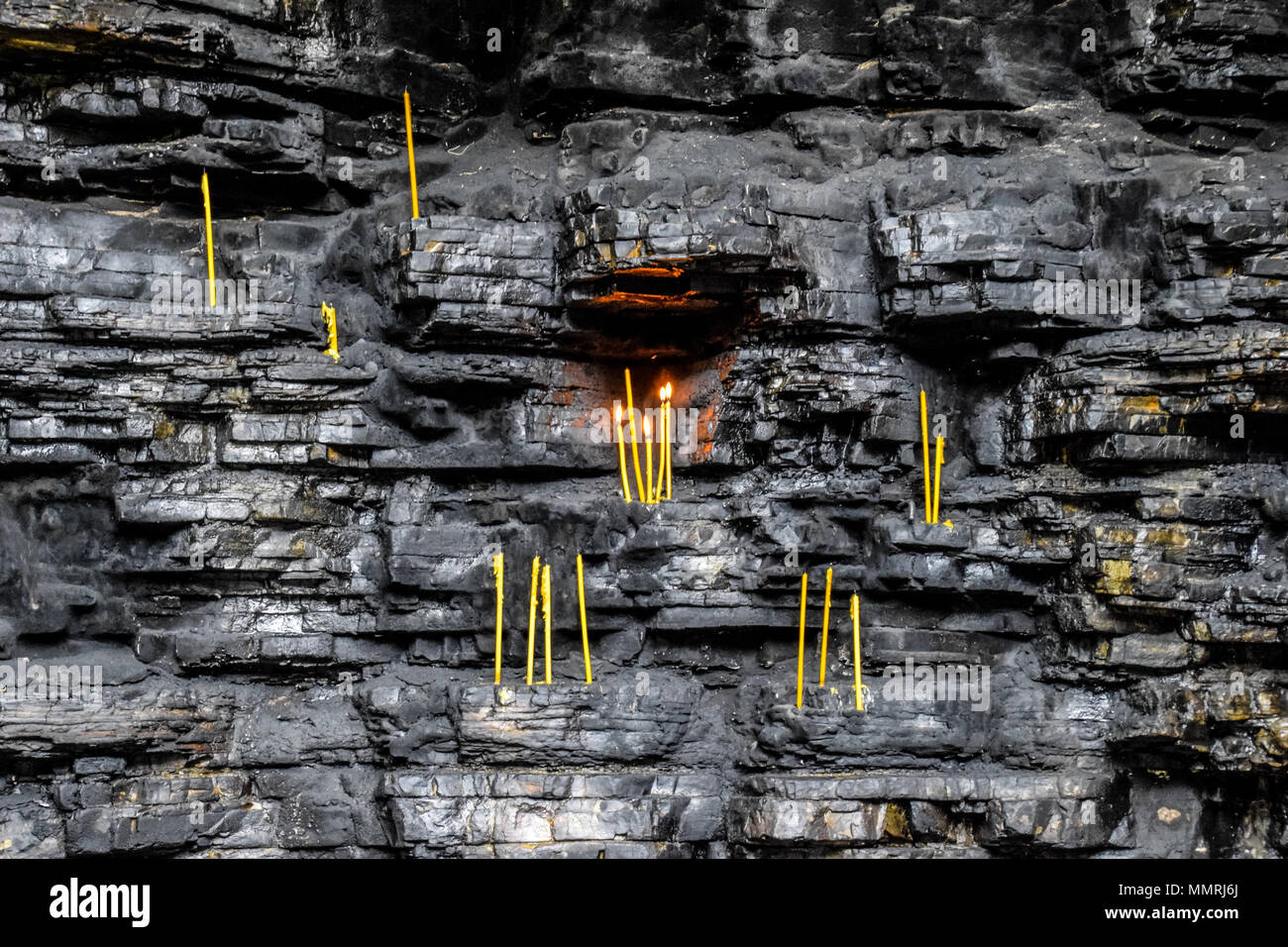 Wax church candles in rock niches. Holy place Stock Photo Alamy