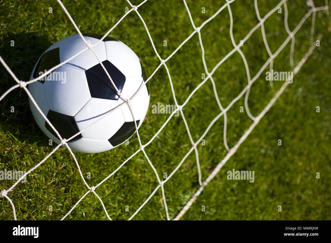 A black and white football behind a net Stock Photo