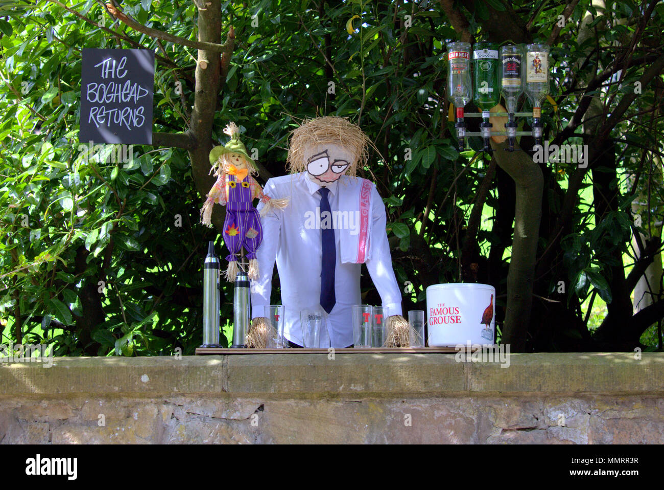 Glasgow, Scotland, UK 12th May.UK Weather: Carmunnock Gala Day  was highlighted by its topical scarecrow competition as sunshine made the day a hot one, The local publican scarecrow positioned high on a wall om busby road.  Gerard Ferry/Alamy news Stock Photo