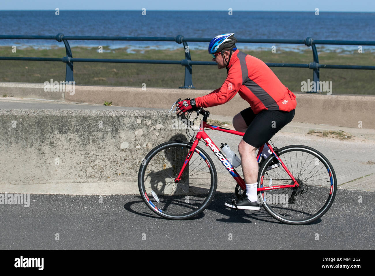 Southport, Merseyside, UK 13/05/2018. UK Weather. Bright colours on a bright sunny day at the coast, as temperatures in the North West are expected to rise.  Residents of the resort take light morning exercise on the seafront promenade at the start of the day. Credit: MediaWorldImages/AlamyLiveNews Stock Photo