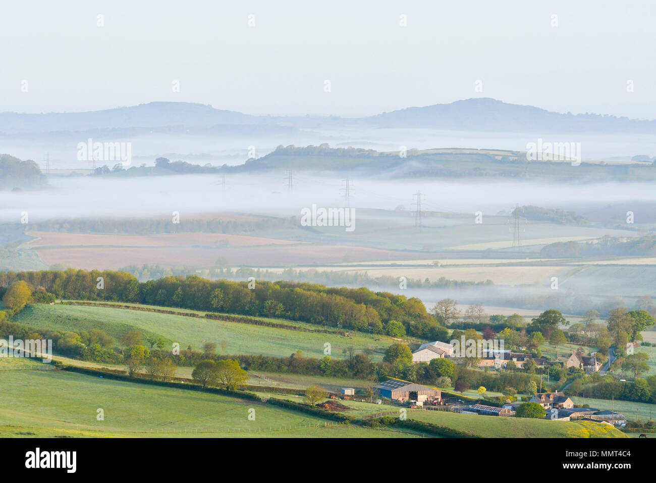 Askerswell, Dorset, UK.  13th May 2018. UK Weather.  View from the hill above the village Askerswell in Dorset looking North West towards Lewesdon Hill with mist the valleys at dawn.  Picture Credit: Graham Hunt/Alamy Live News Stock Photo