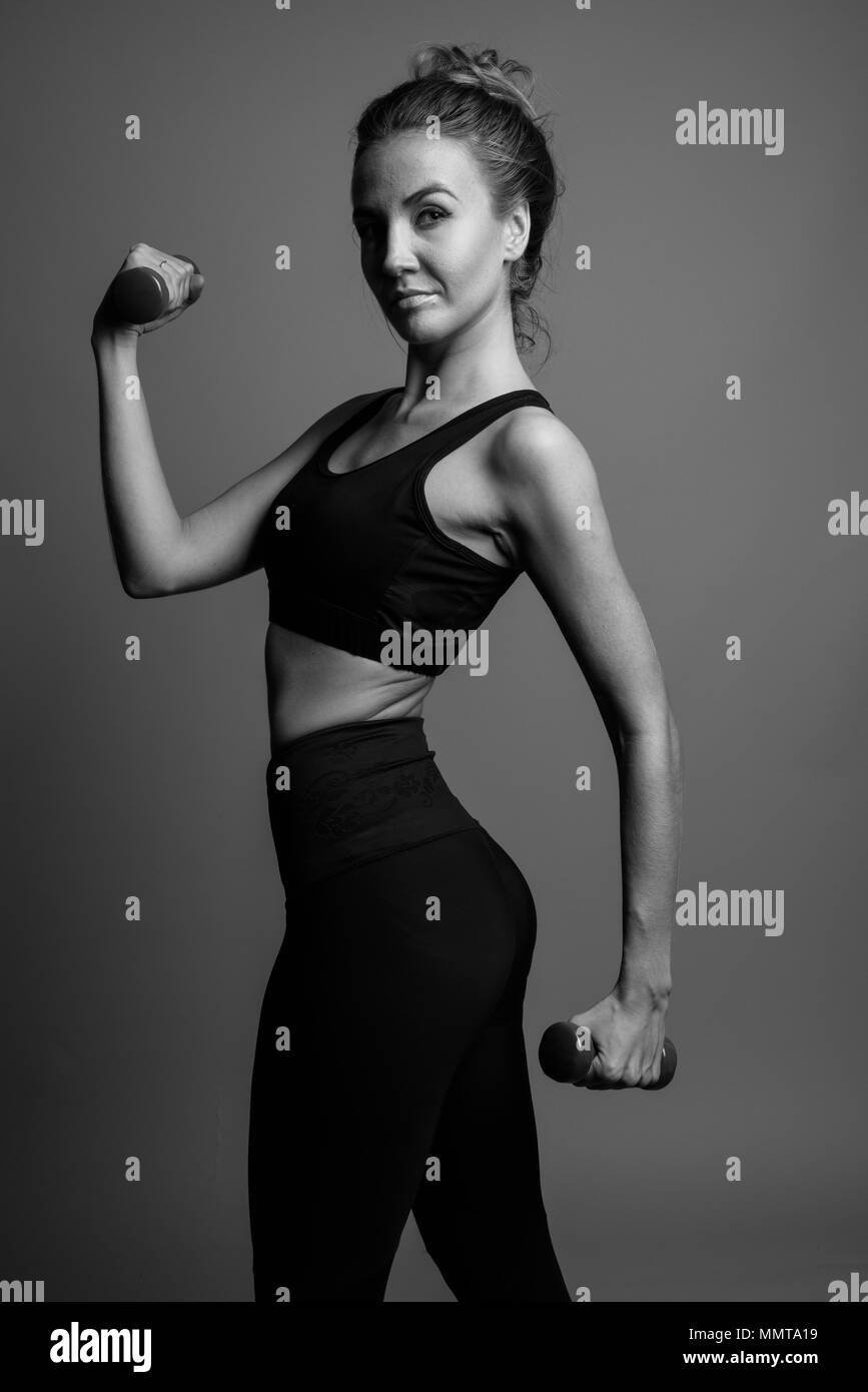 Young beautiful woman ready for gym against gray background in b Stock Photo
