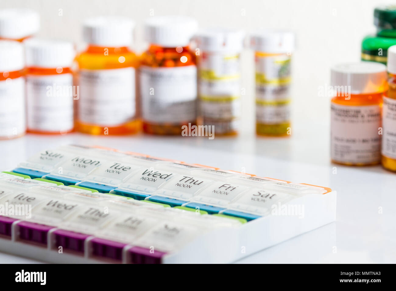 organizer for a daily regime of prescriptions drugs with pill bottles in the background Stock Photo
