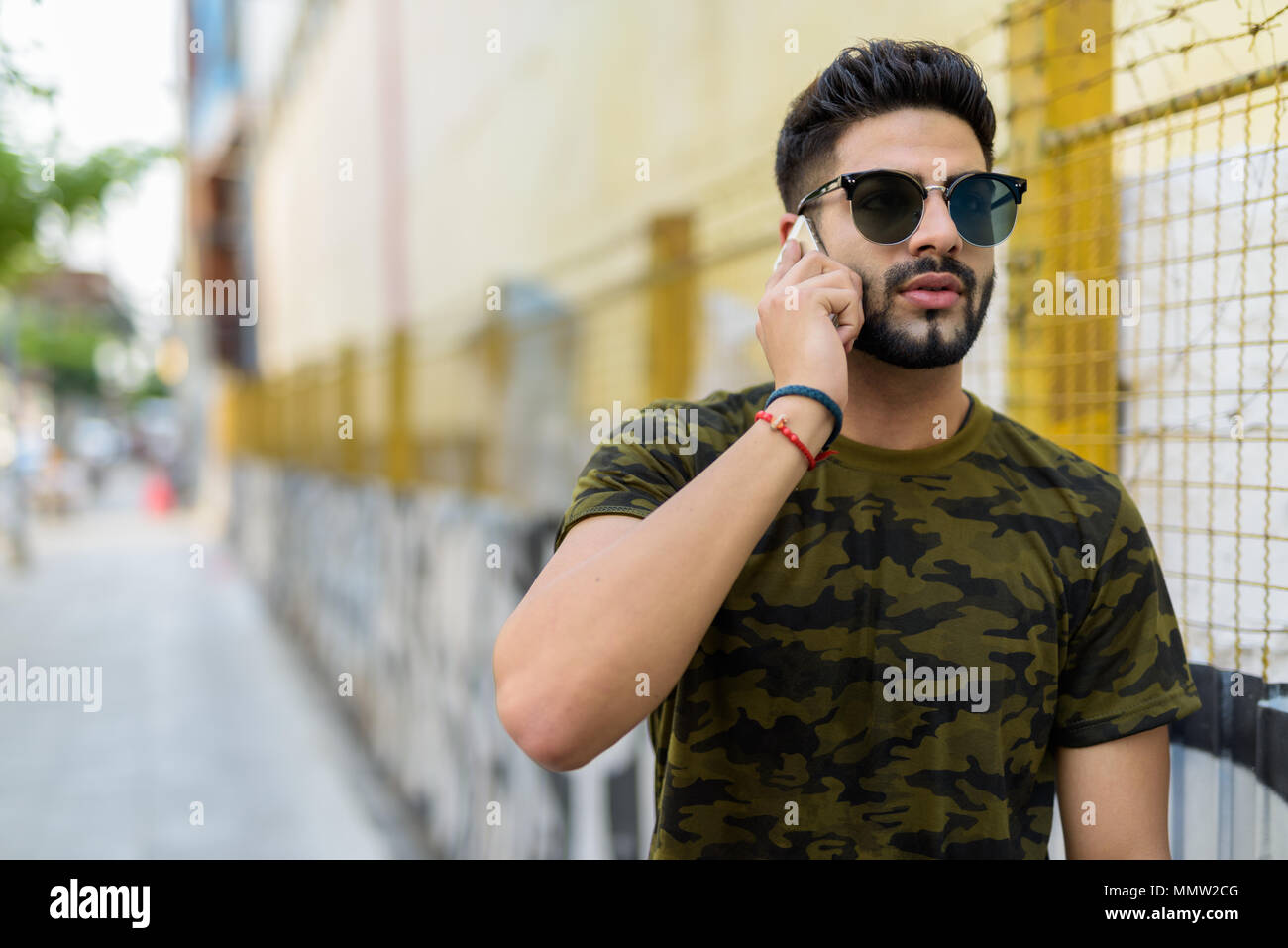 Young handsome Indian man wearing sunglasses while thinking and  Stock Photo