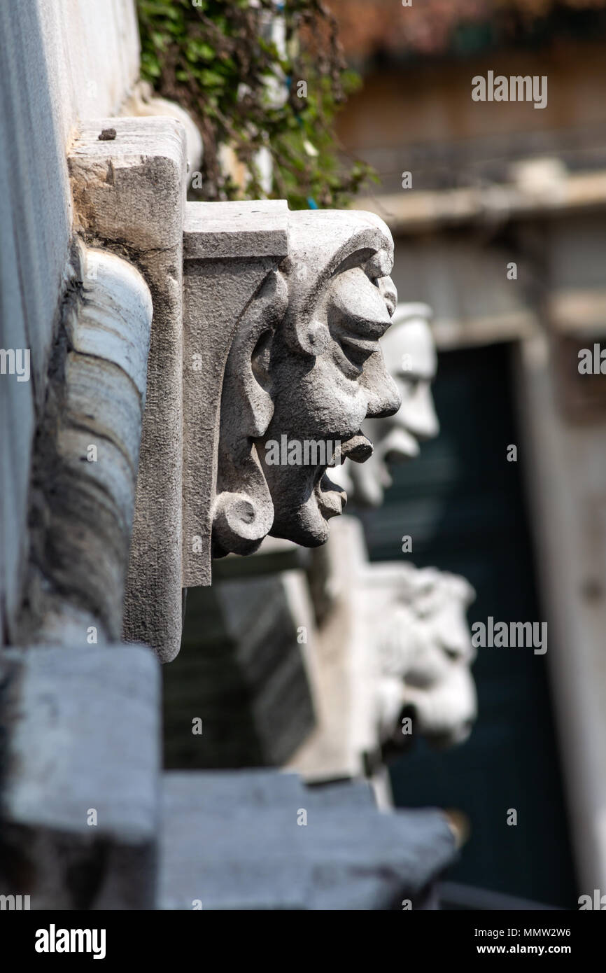 Head / Face carvings on side of bridge, Venice, Italy Stock Photo