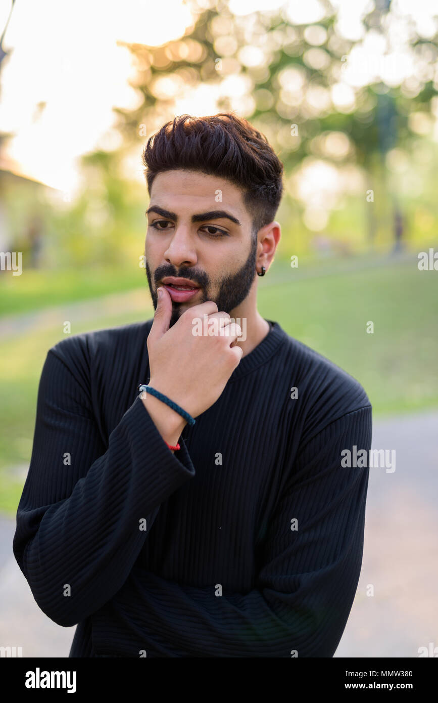 Young handsome Indian man thinking on the side of the street at  Stock Photo