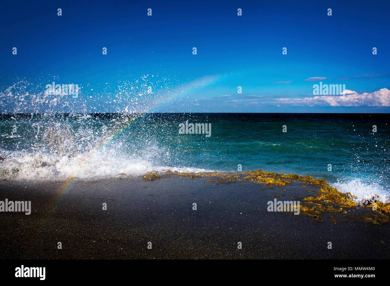 Crashing waves at Blowing Rocks Preserve in Florida create a momentary rainbow. Stock Photo
