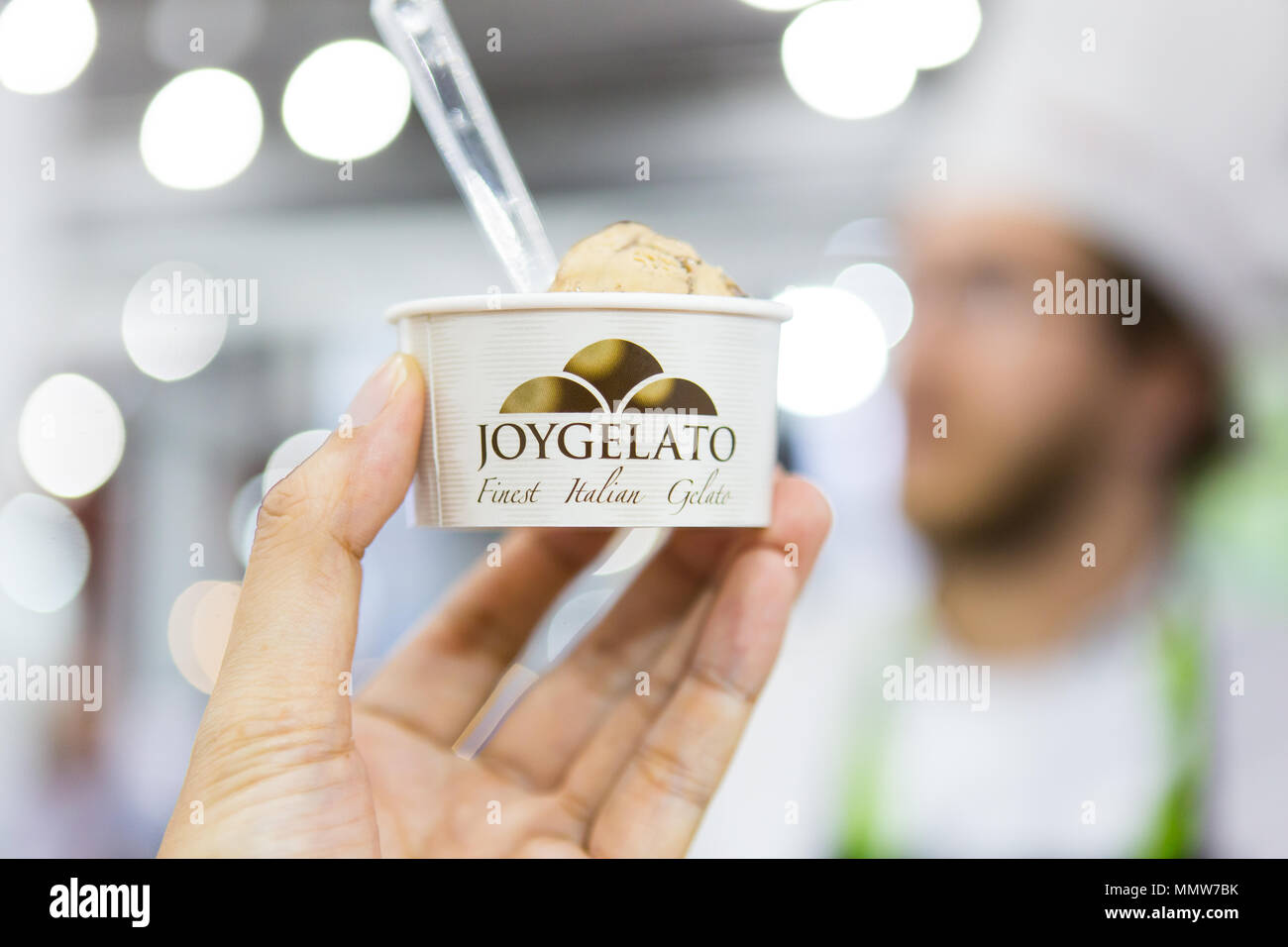 A hand holding a paper cup of Gelato coffee flavour at a food exhibition, handed by the ice-cream chef. Singapore Stock Photo