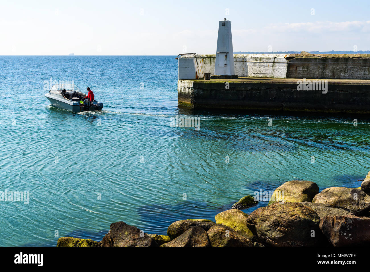 Alabodarna, Sweden - April 29, 2018: Documentary of everyday life and place. Small motorboat leaving the harbor on a sunny and hazy day. Stock Photo