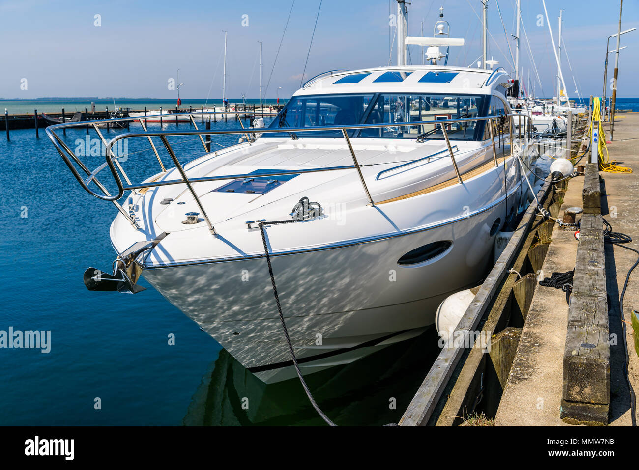 Luxurious motorboat tied to a pier in a marina. Boat seen from the front. Logos and id removed. Stock Photo