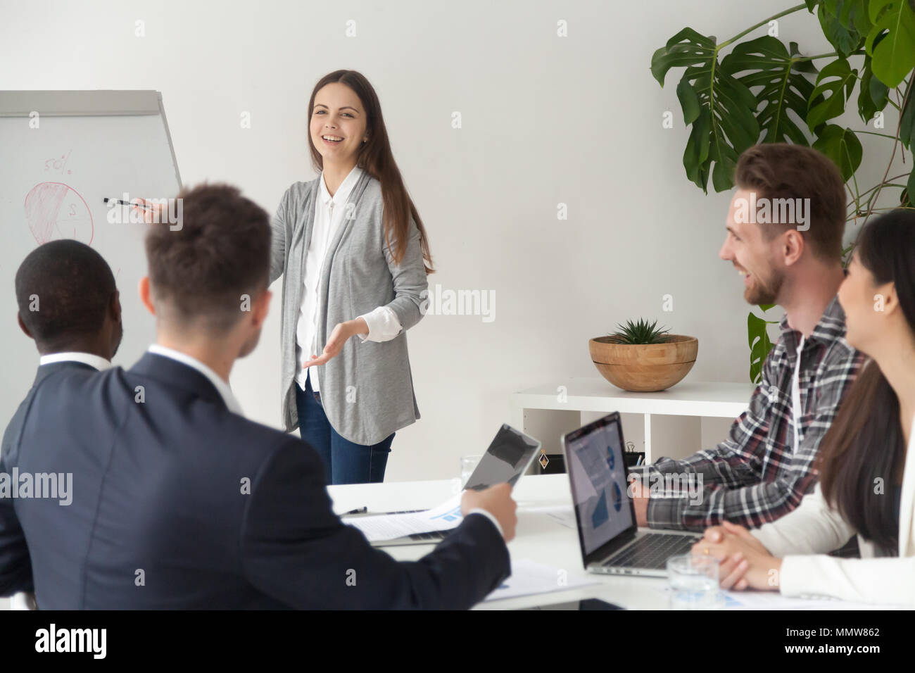 Smiling young employee giving presentation working with flipchar Stock Photo
