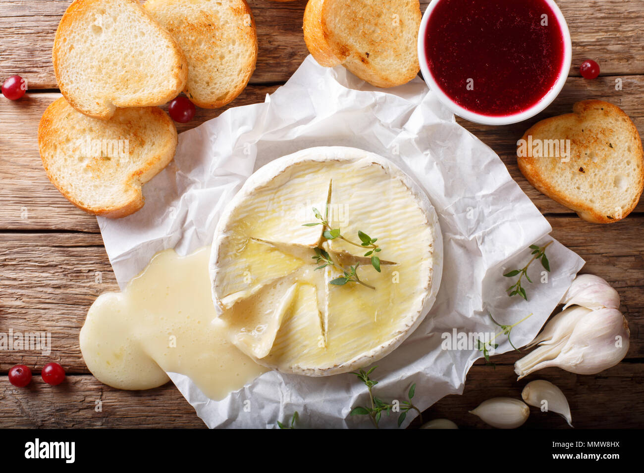 baked camembert cheese with thyme and garlic served with roasted bread close-up on the table. Horizontal top view from above Stock Photo