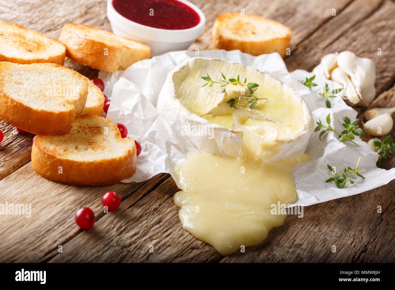 Melted spicy Camembert cheese with garlic, thyme and olive oil closeup