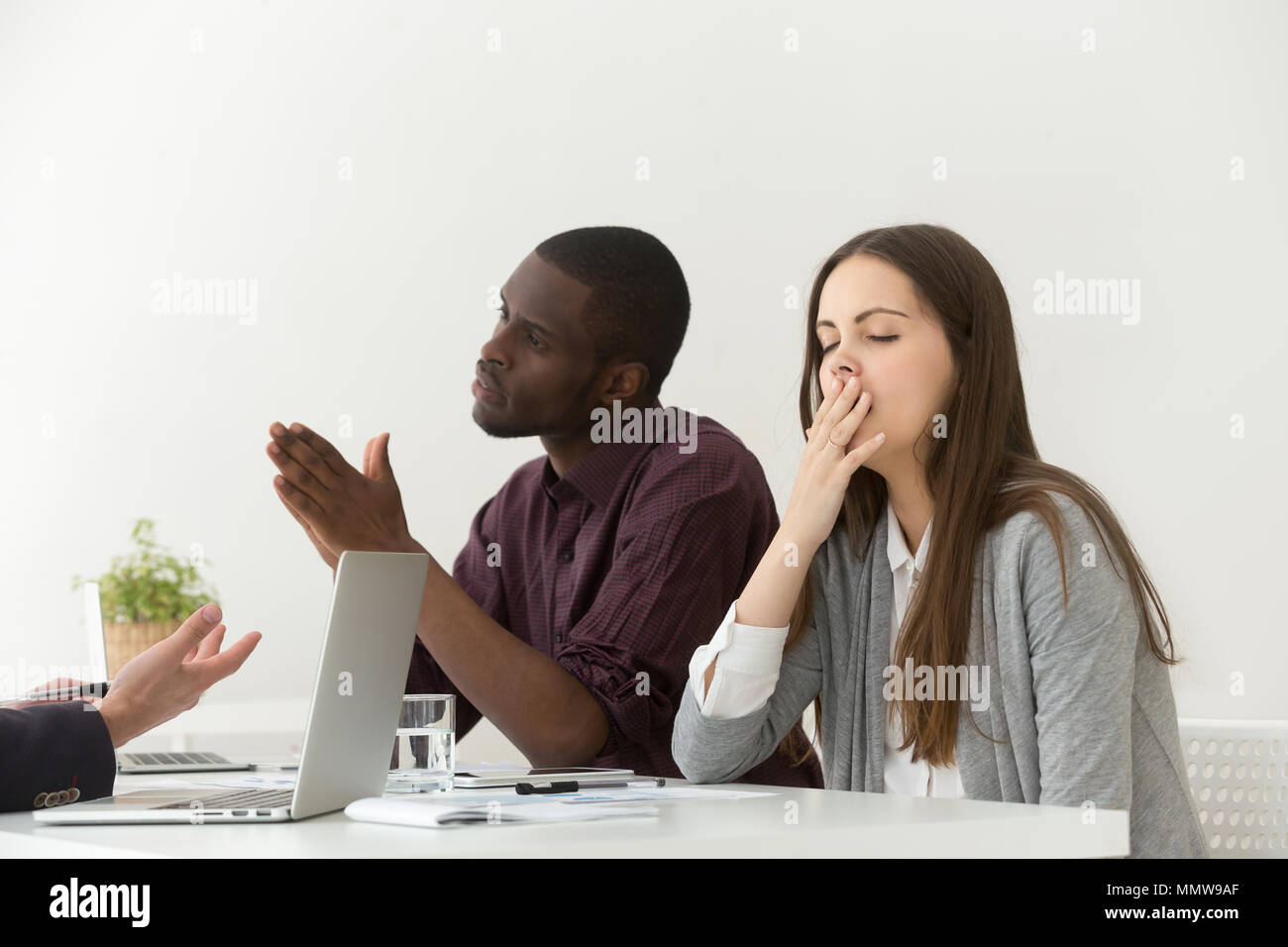 Tired bored businesswoman yawning at boring meeting with diverse Stock Photo
