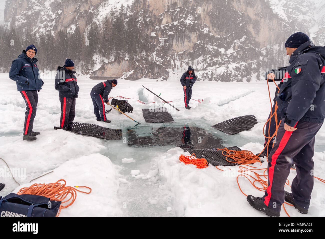 Braies Lake, Italy - March 10th, 2018:  Italians Carabinieri dig a big hole deep into the ice to let rescue divers entering into the lake, Braies, Ita Stock Photo