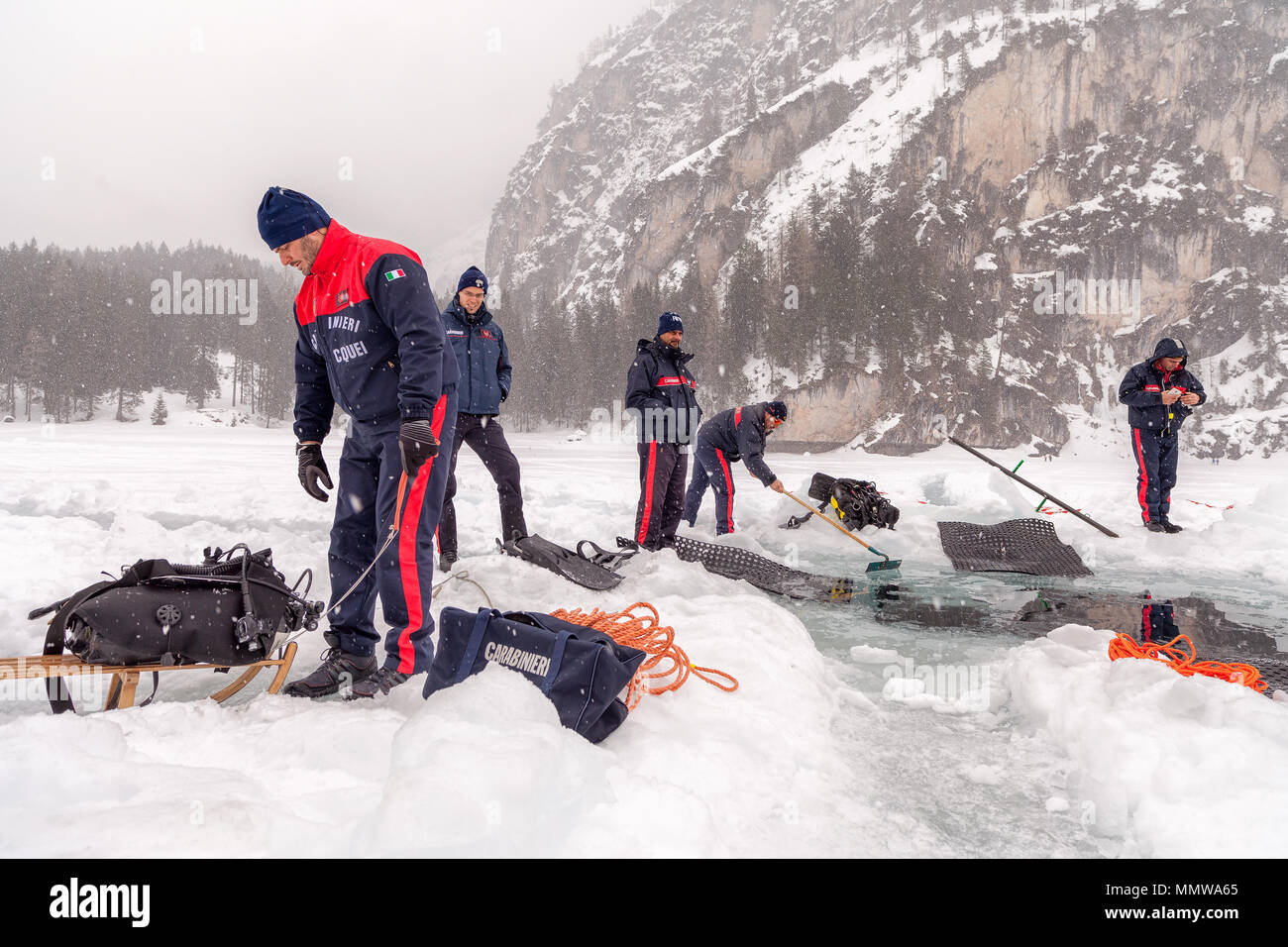 Braies Lake, Italy - March 10th, 2018:  Italians Carabinieri dig a big hole deep into the ice to let rescue divers entering into the lake, Braies, Ita Stock Photo