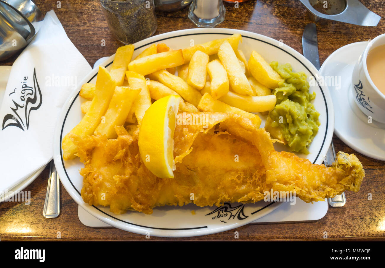 Excellent fish and chips at the famous Magpie Cafe in Whitby small Haddock served with mushy peas a slice of lemon and a cup of tea Stock Photo