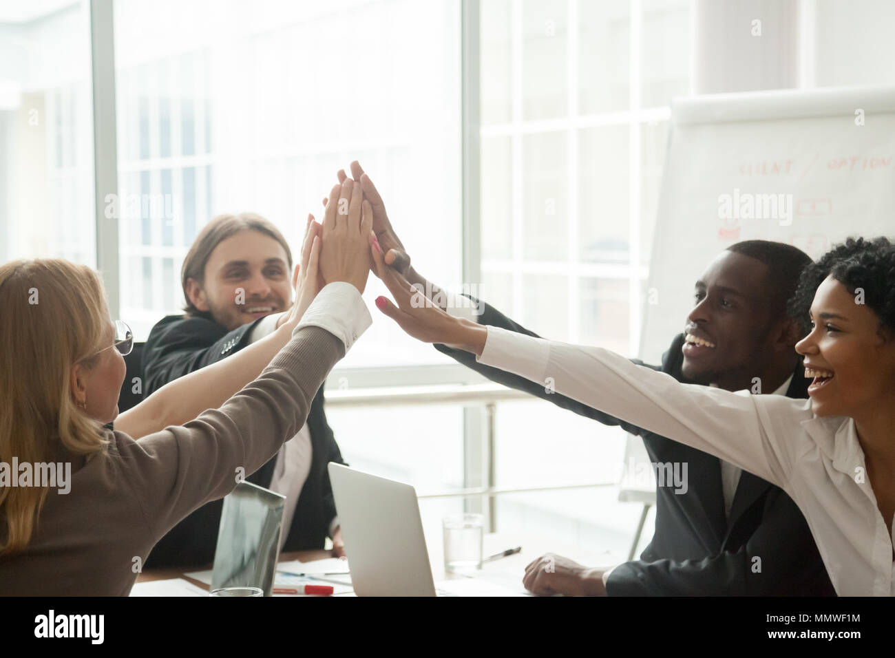 Happy motivated diverse business team giving high five at meetin Stock ...