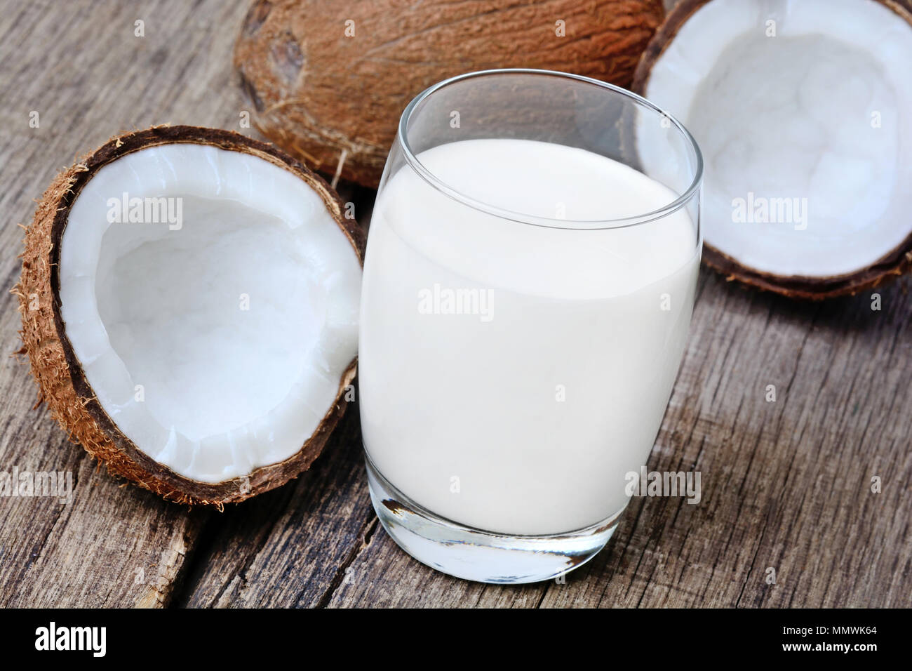 Coconut milk in a glass on rustic wooden table Stock Photo
