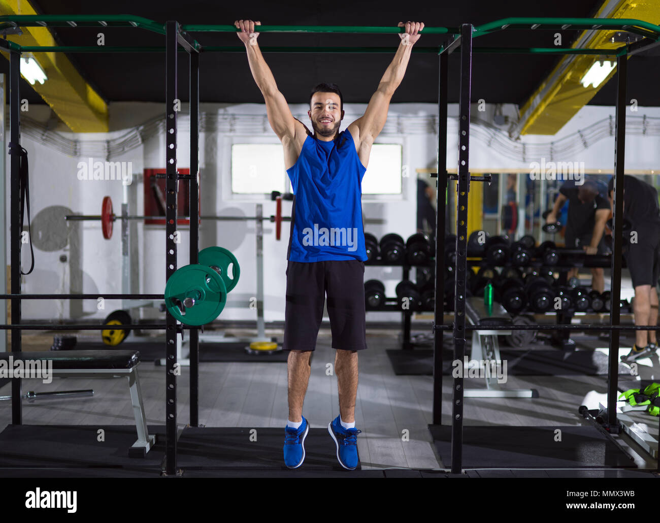 young muscular man doing pull ups on the horizontal bar as part of ...