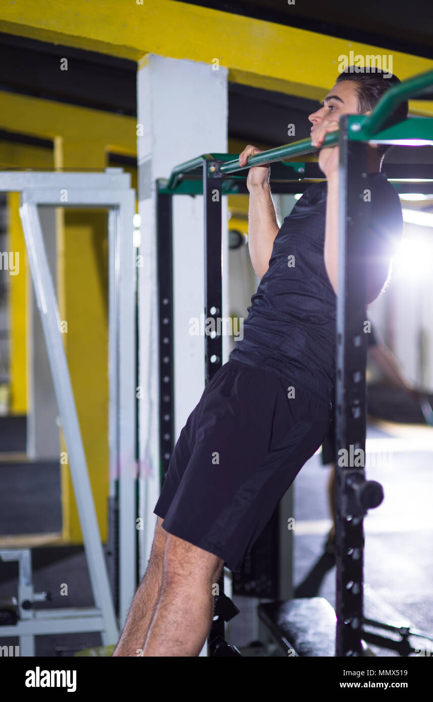 young muscular man doing pull ups on the horizontal bar as part of ...