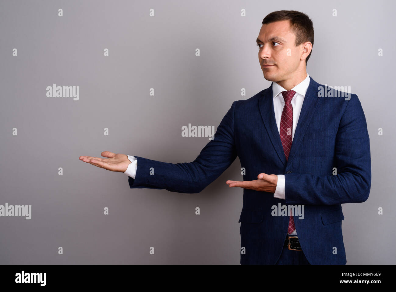 Businessman wearing suit against gray background Stock Photo - Alamy