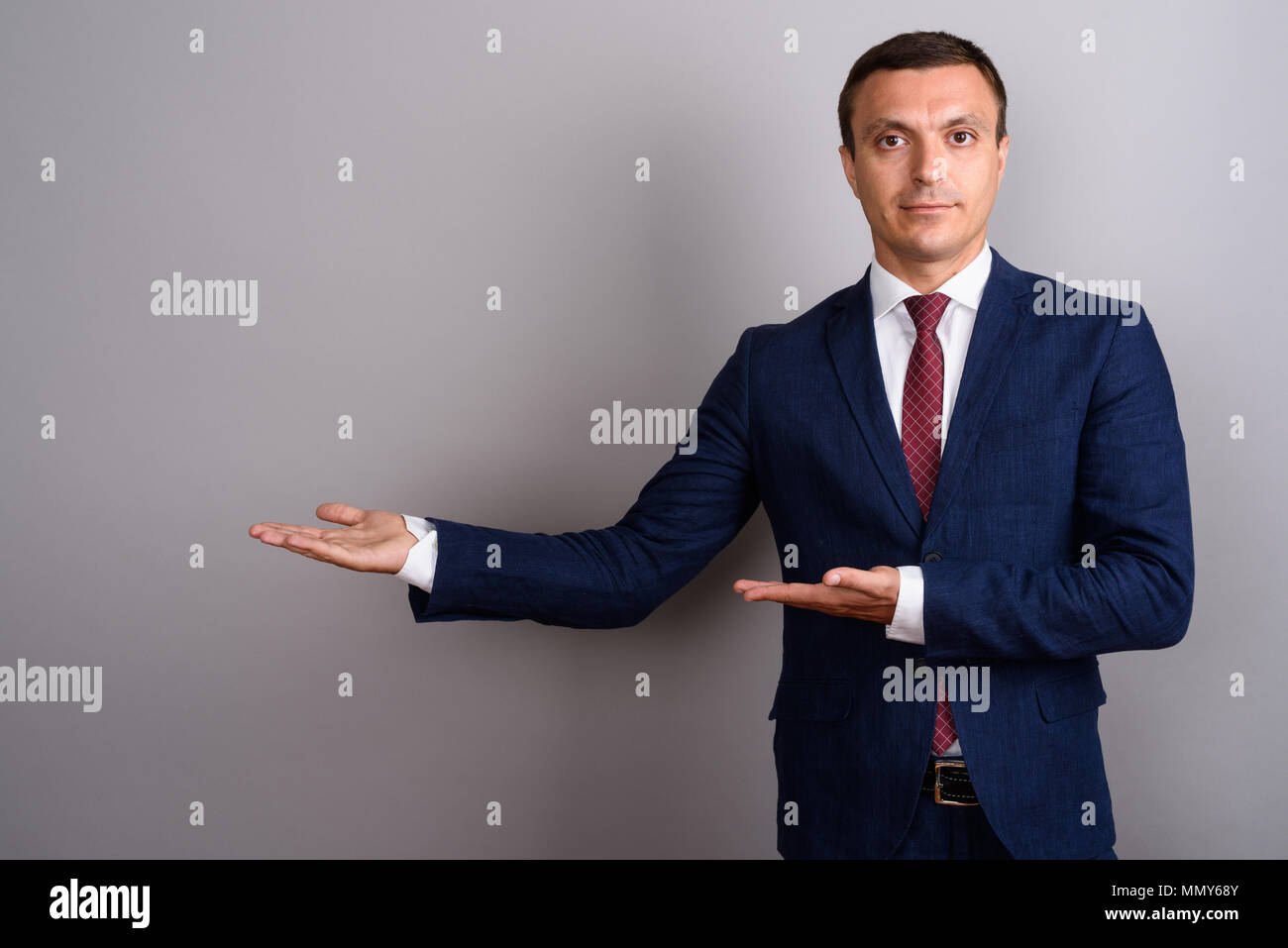 Businessman wearing suit against gray background Stock Photo - Alamy