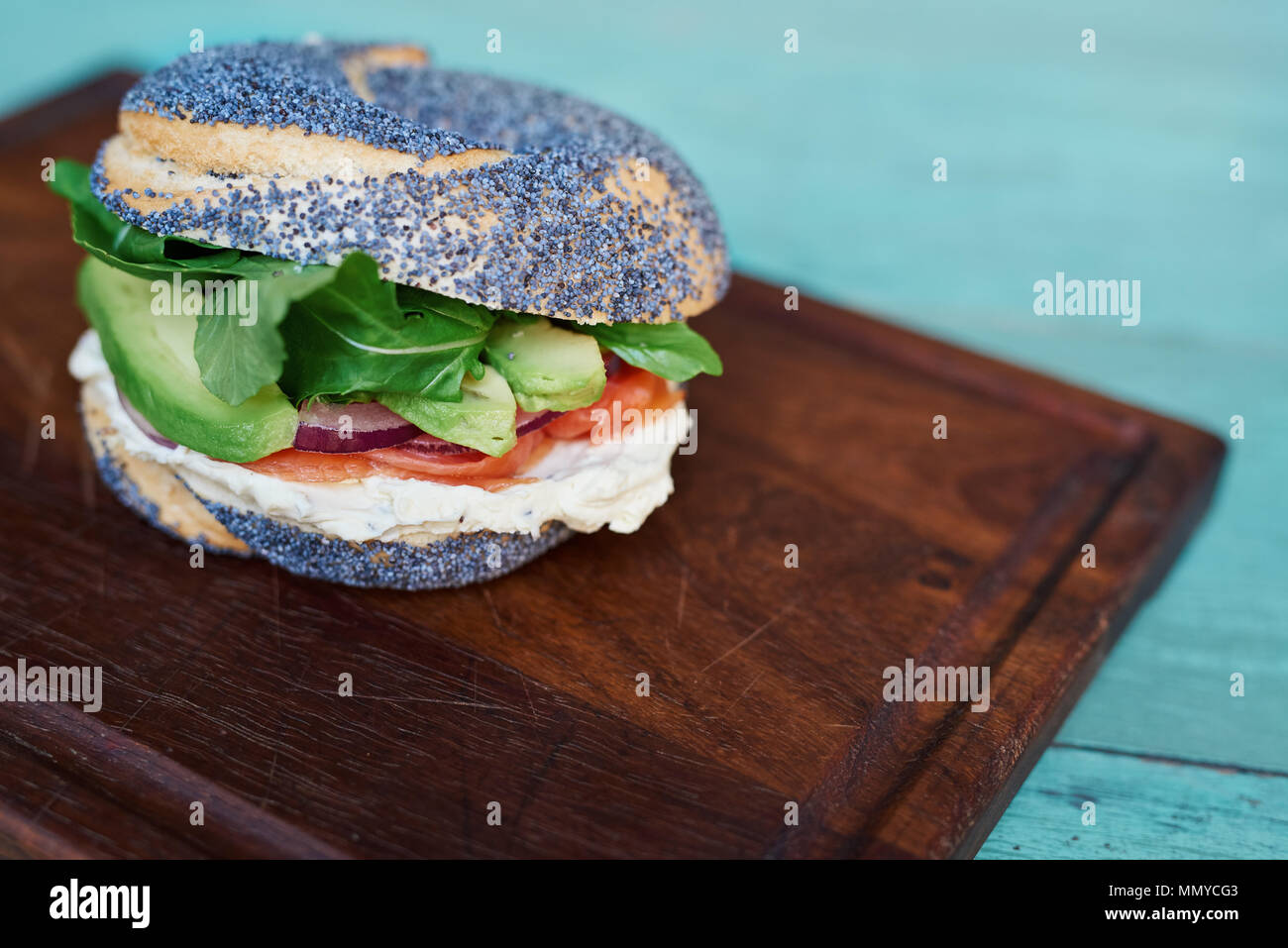 Delicious salmon and cream cheese bagel on a turquoise table Stock Photo