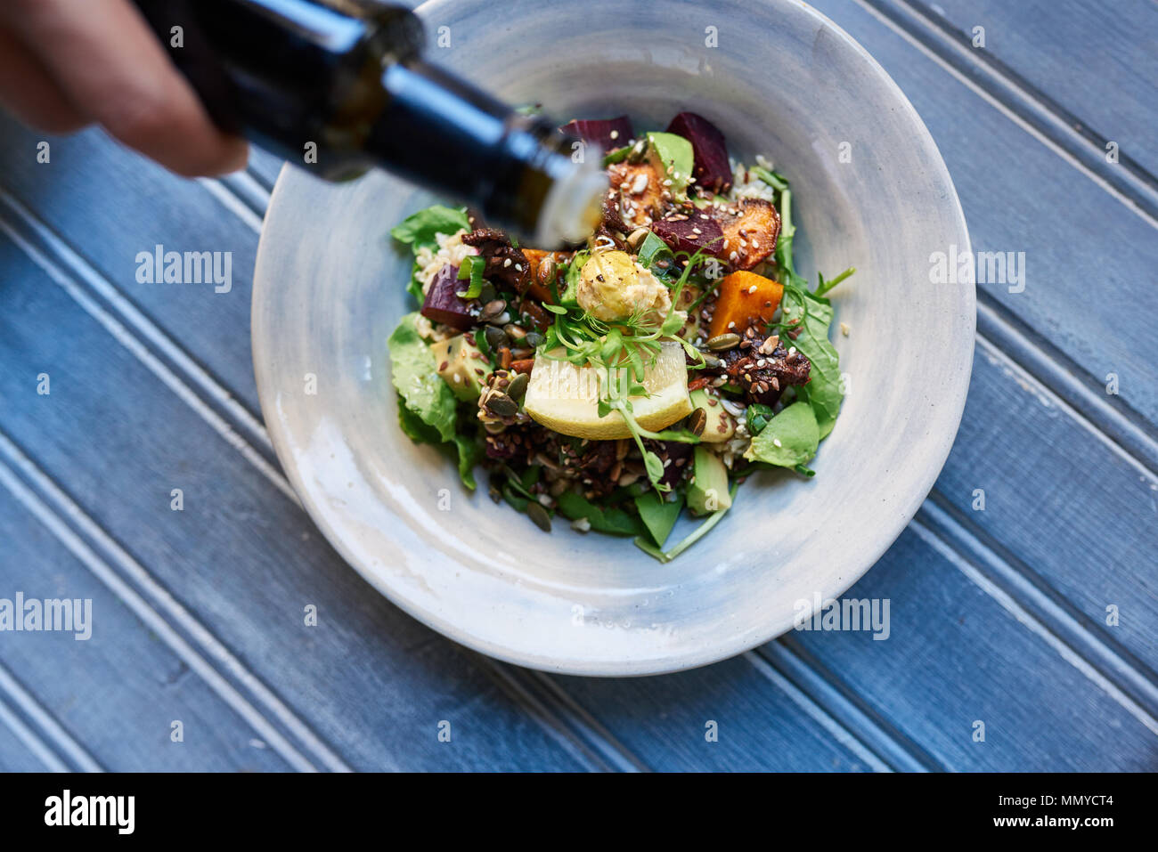 Man pouring dressing over a healthy mixed vegetable salad Stock Photo