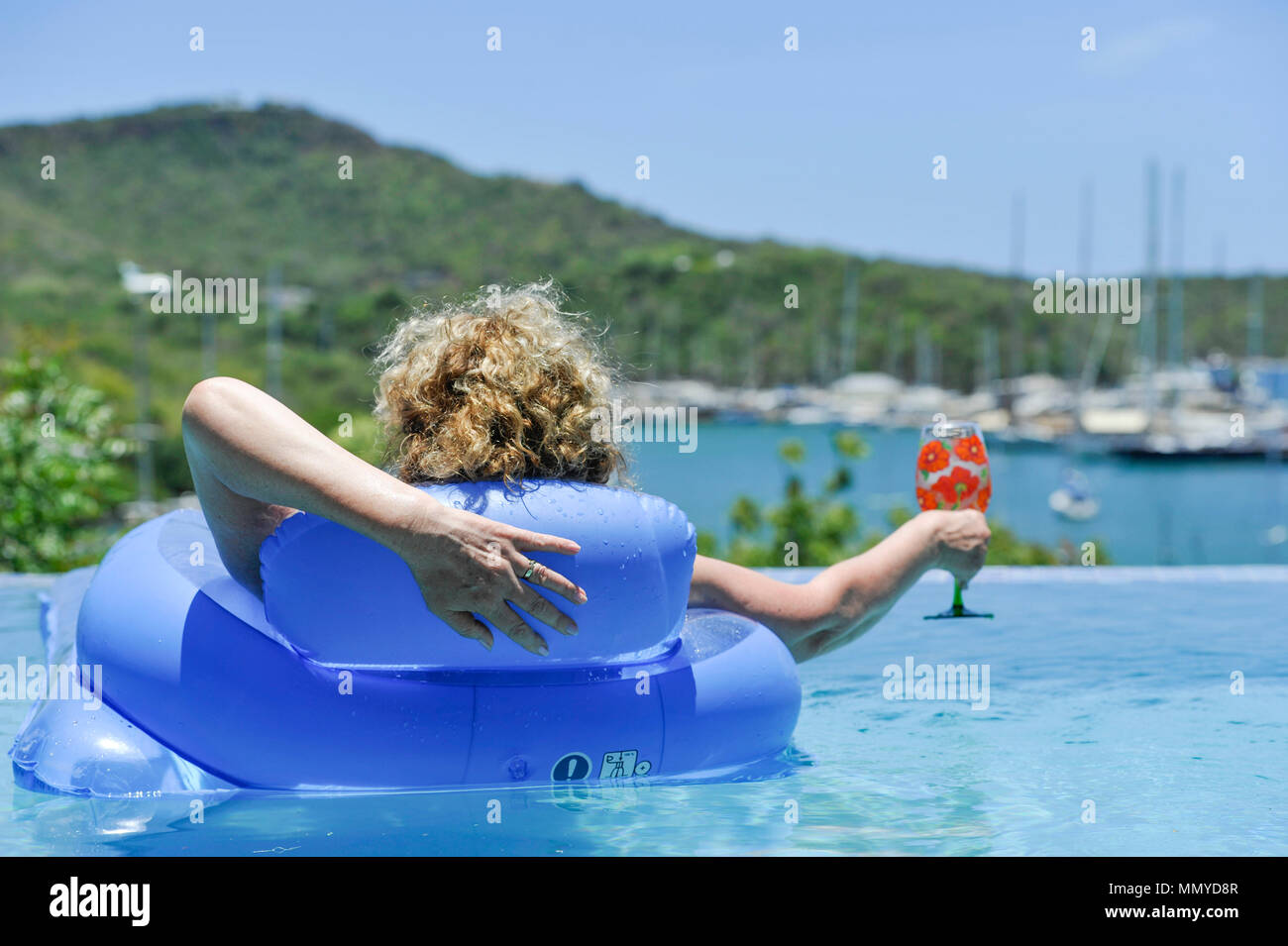 Antigua Lesser Antilles islands in the Caribbean West Indies - Woman on inflatable in an infinity swimming pool view overlooking English Harbour Stock Photo