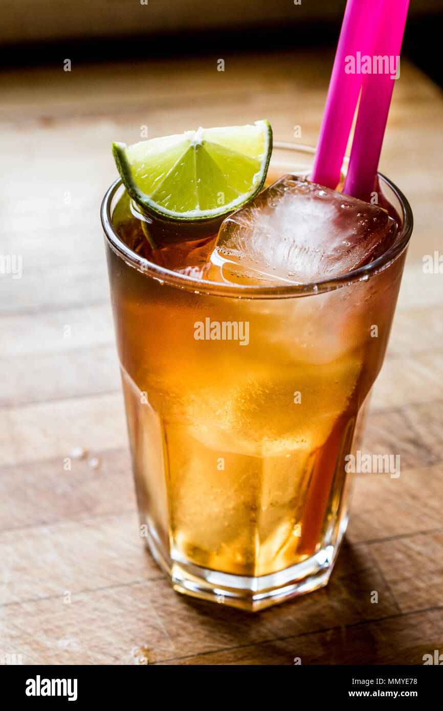Long island iced tea cocktail with lime, ice and served with pink straw