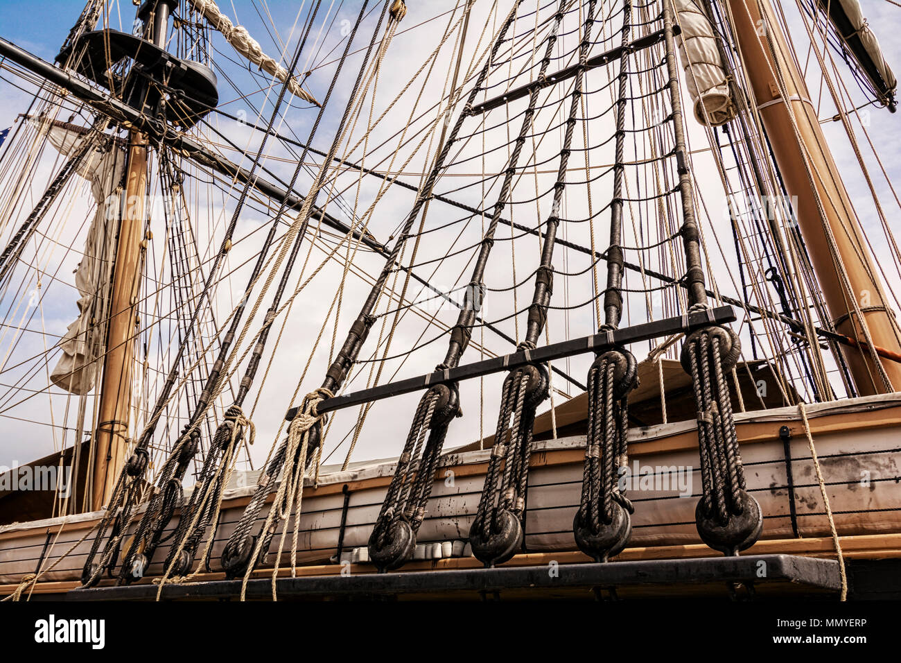 The masts and rigging of the tall ship U.S. Brig Niagara against a blue, cloud filled sky. Stock Photo