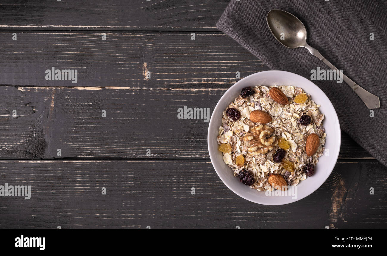 Muesli in white bowl on gray natural desk and with spoon on napkin. Stock Photo
