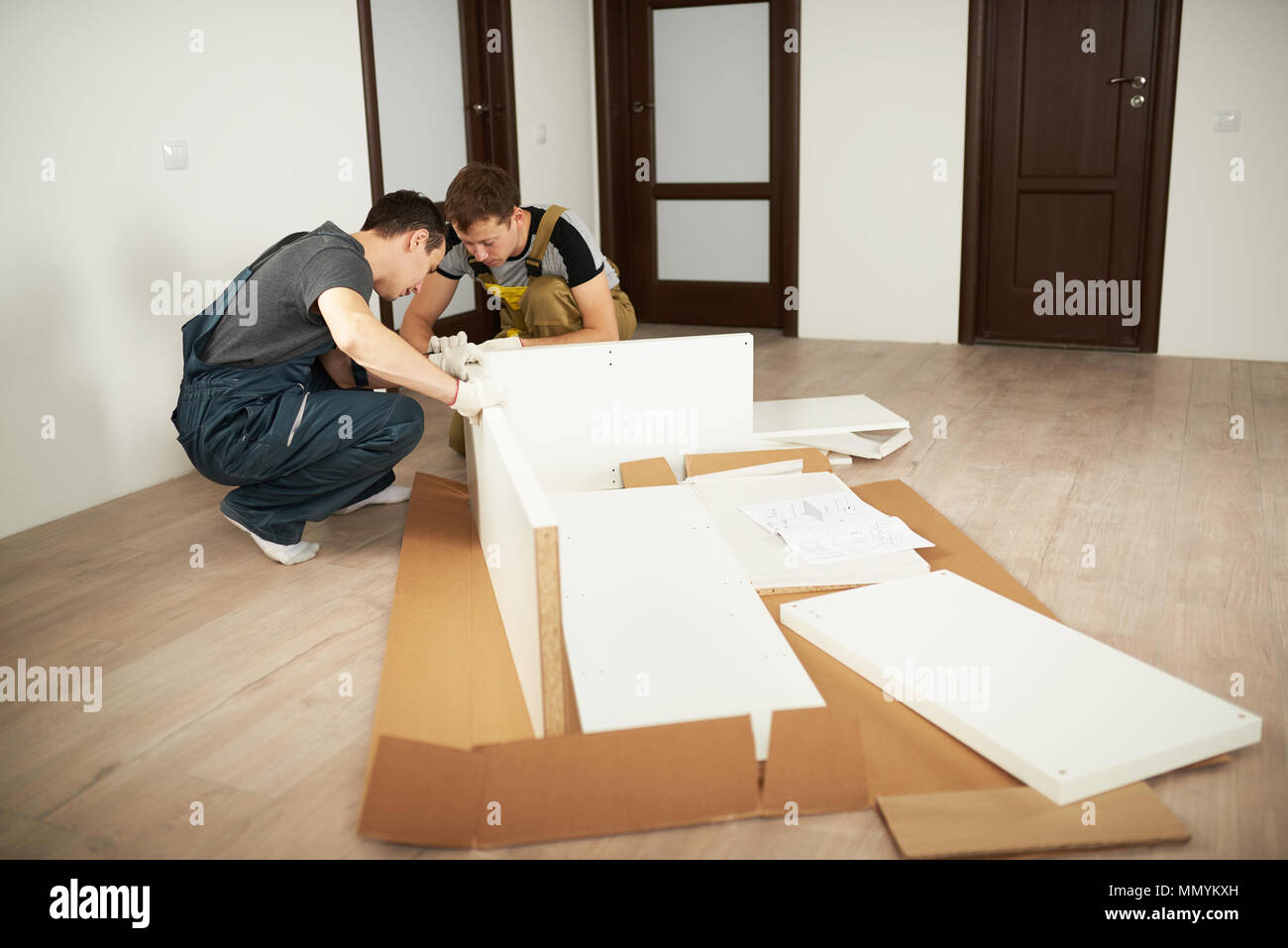 Two professional workers installing furniture in apartment. Furniture