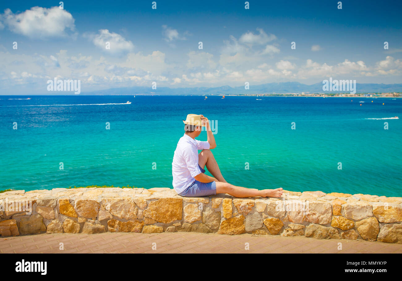 Salou resort. Costa dorada coastline. Young man enjoying summer sea view. Man on blue sea and clear sky background. Stock Photo