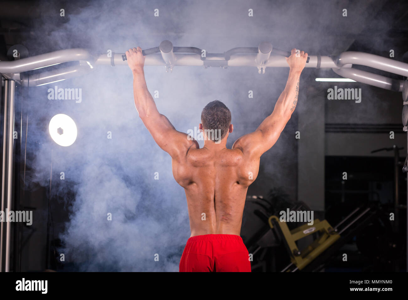 Strong young man doing pull up exercise on horizontal bar in gym Stock ...